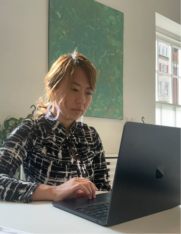 Executive advisor working on a laptop in a bright office, reflecting focused strategic work and leadership support.