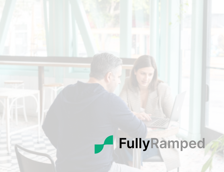 Two professionals discussing sales strategy in a bright modern cafe, representing an exclusive interview with FullyRamped founder Aaron Marks.