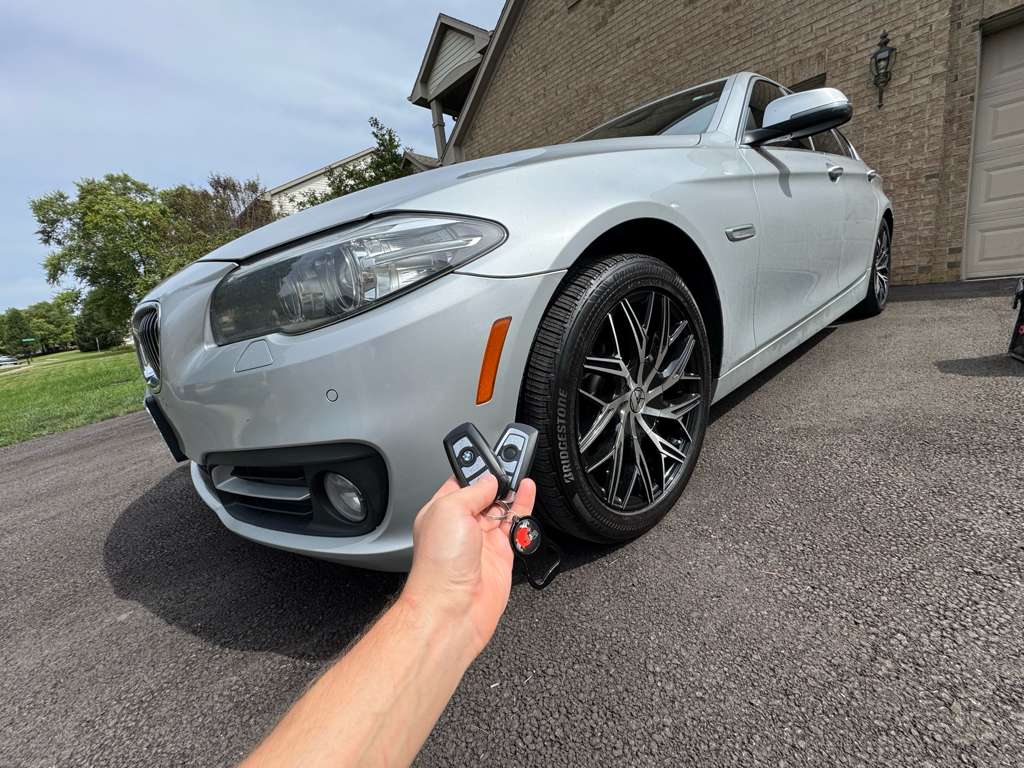 Technician holding two BMW key fobs – mobile key fob programming service