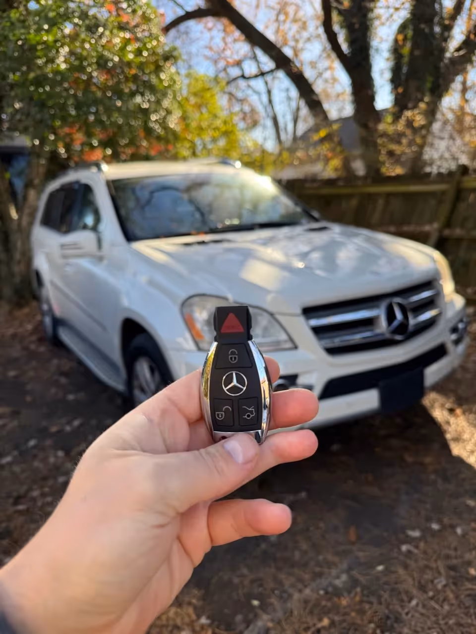 Mercedes smart key held in front of a white Mercedes SUV after key programming