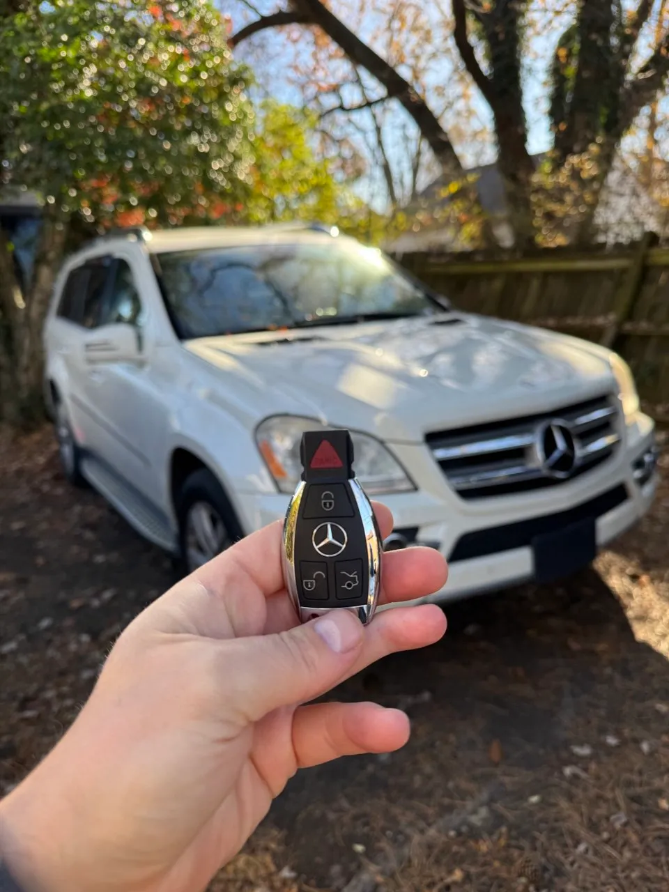 Mercedes smart key held in front of a white Mercedes SUV after key programming