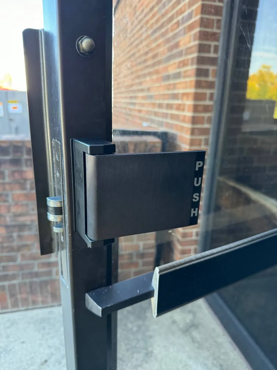 Commercial door pivot hinge repair on metal storefront door.