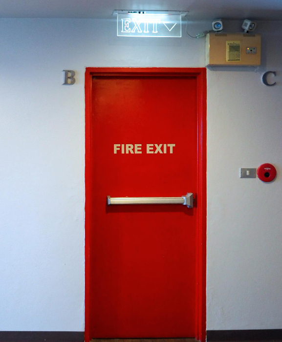 Fire exit door with panic bar exit device under illuminated EXIT sign