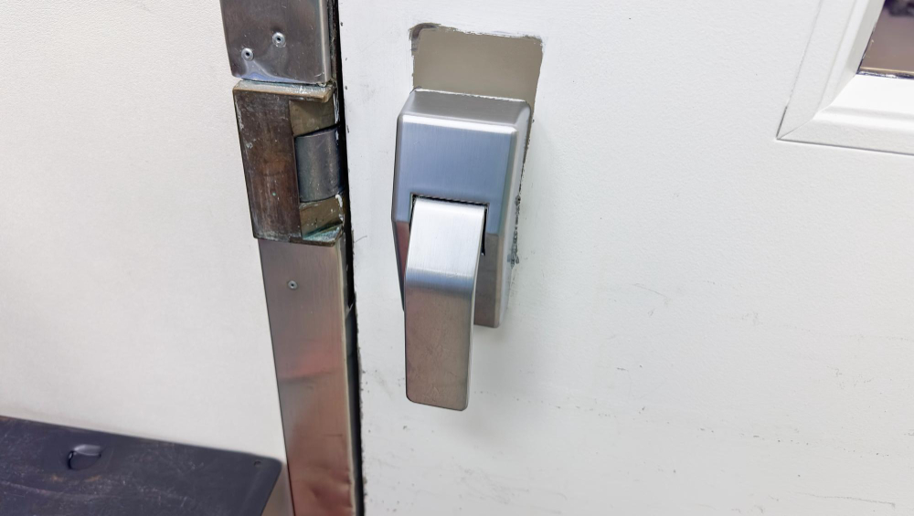 Close-up of commercial door latch and exit device trim after panic bar repair