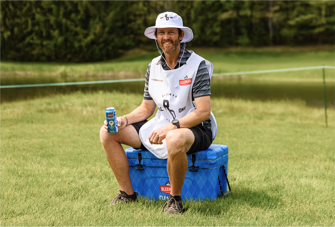 Dave Markle, PGA tour caddy sitting on a Sleeman's cooler enjoying a beer.