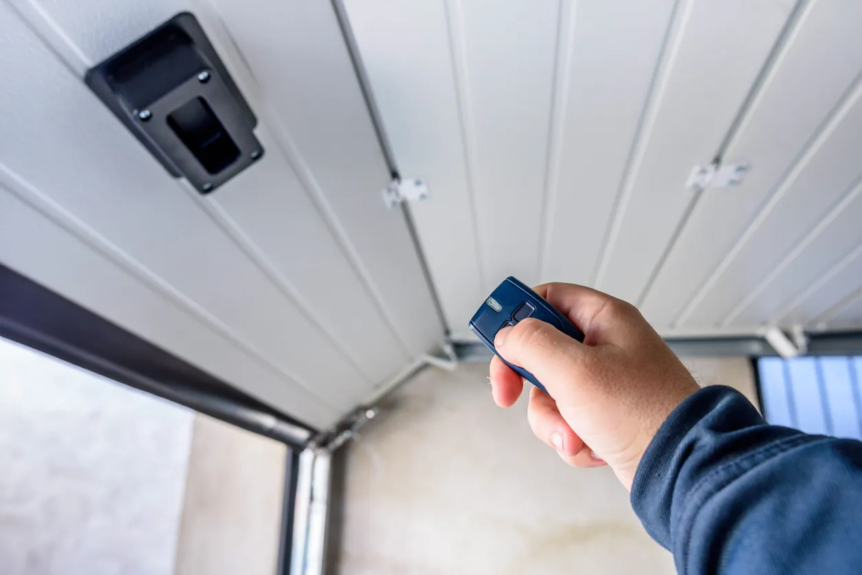 A close-up of a blue paneled garage door with decorative black handles and a row of windows on top.