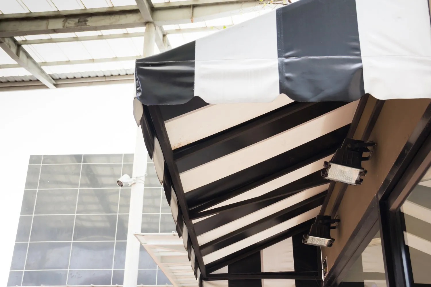 A new black and white striped awning with a scalloped edge is installed above a storefront, with black and white checkered fabric on its top surface.
