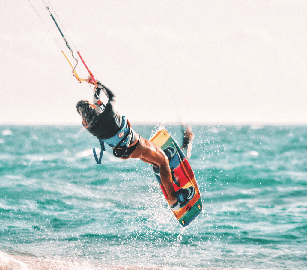 Kitesurfer performing an aerial trick near Floripa Surf and Yoga Retreat in Sicily, showcasing exciting kitesurf conditions and water sports experience