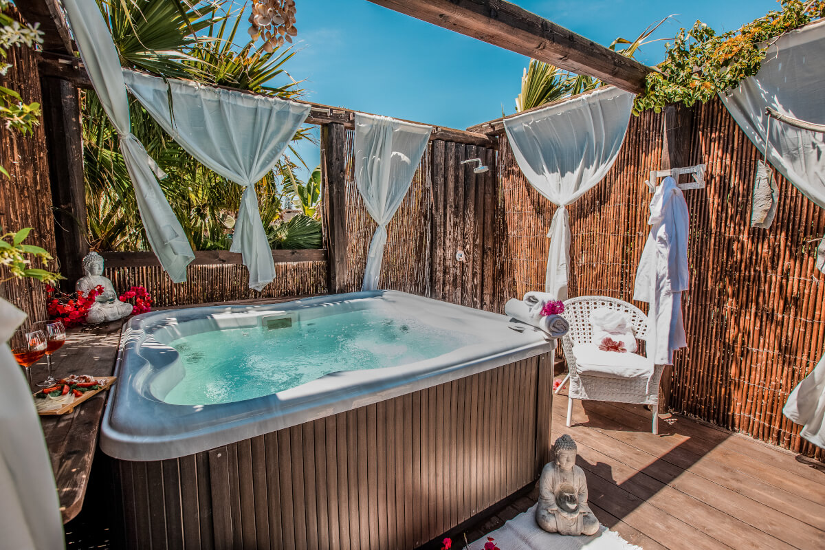 Outdoor whirlpool jacuzzi at Floripa Surf and Yoga Retreat in Sicily, offering a peaceful wellness experience with bamboo privacy, tropical greenery, and spa vibes
