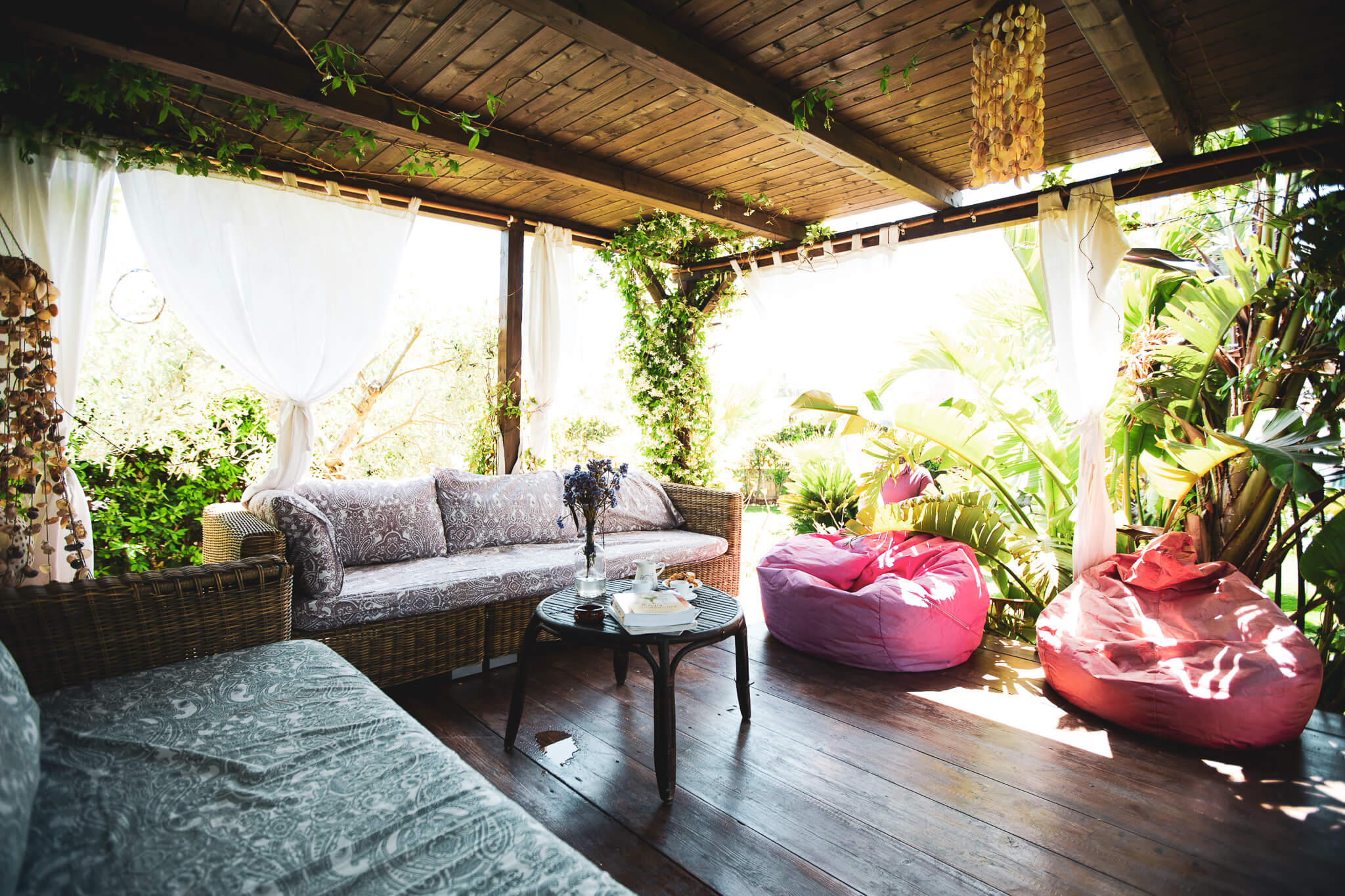 Outdoor common lounge area at Floripa Surf and Yoga Retreat in Sicily with comfy seating, lush plants, and peaceful natural light

