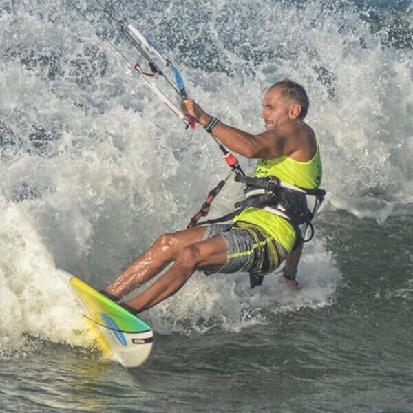 Ettore, experienced kitesurf instructor at Floripa Surf and Yoga House in Sicily, riding a wave during a professional kitesurf session

