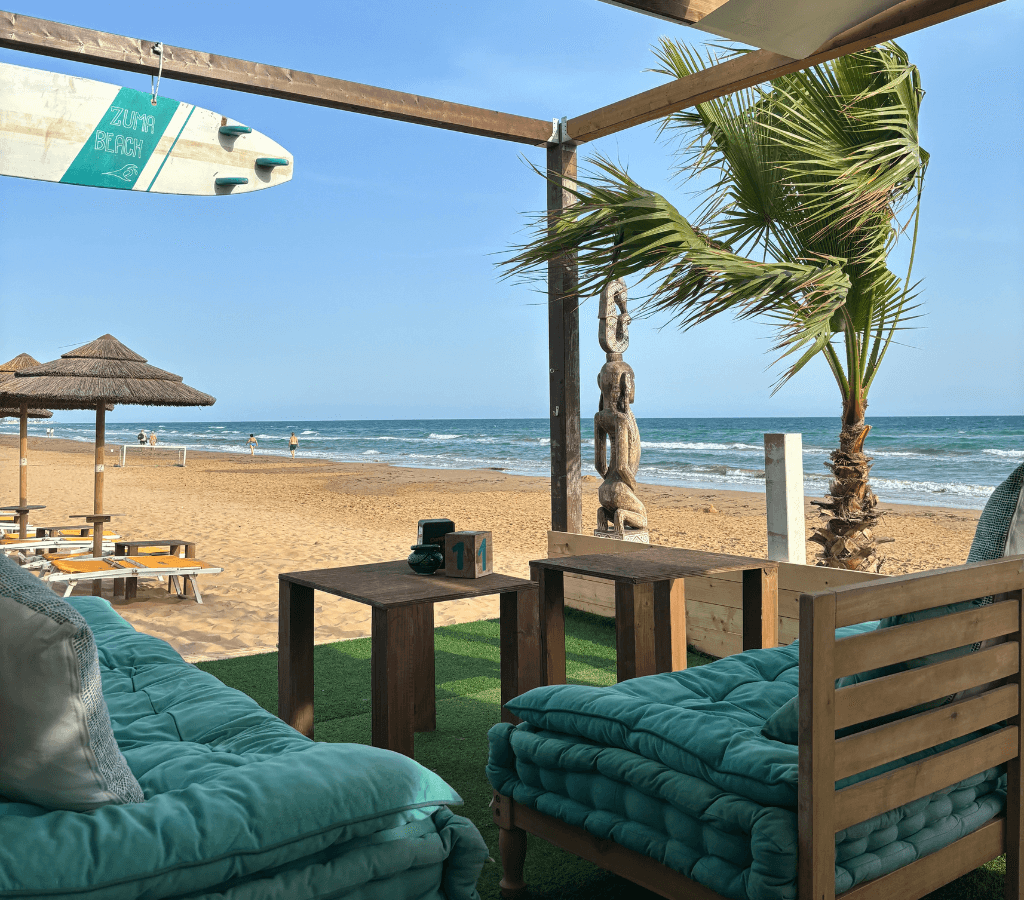 Beachfront lounge at Floripa Surf House in Sicily with ocean view, surfboard, beach time, cocktails