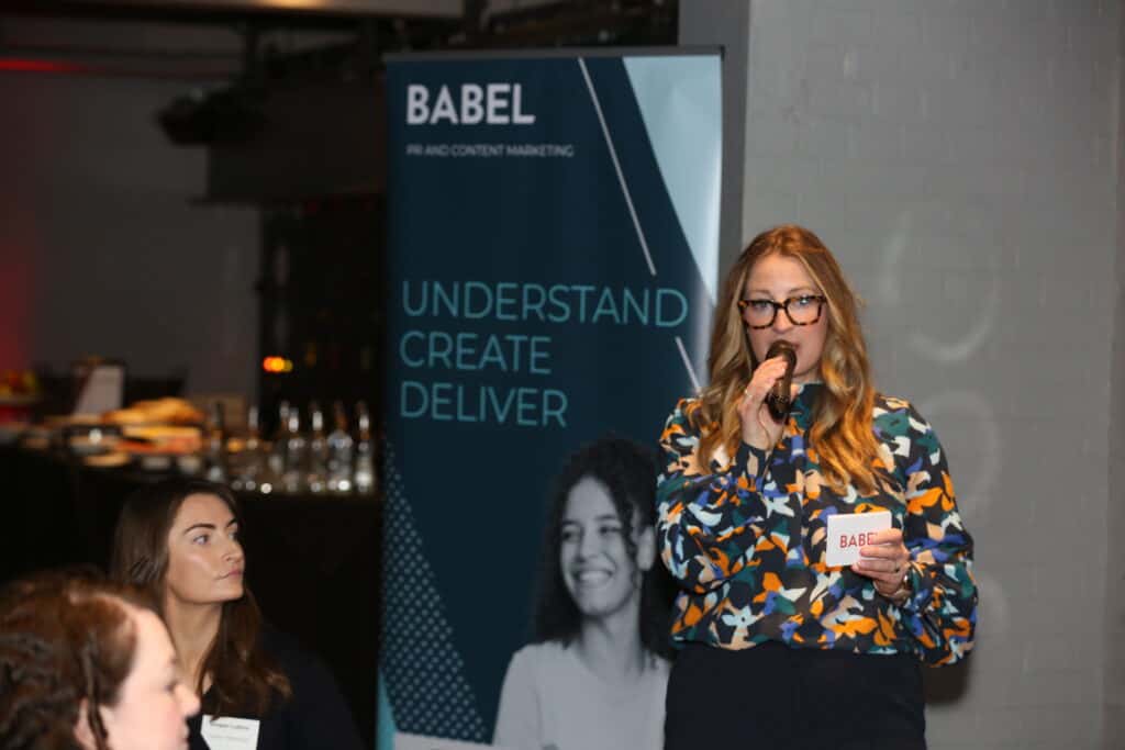 Women hosting event speaking into microphone