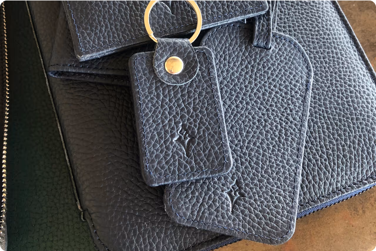 Luxury leather portfolio and keychain with Comtrade System Integration logo, featuring textured navy blue design.