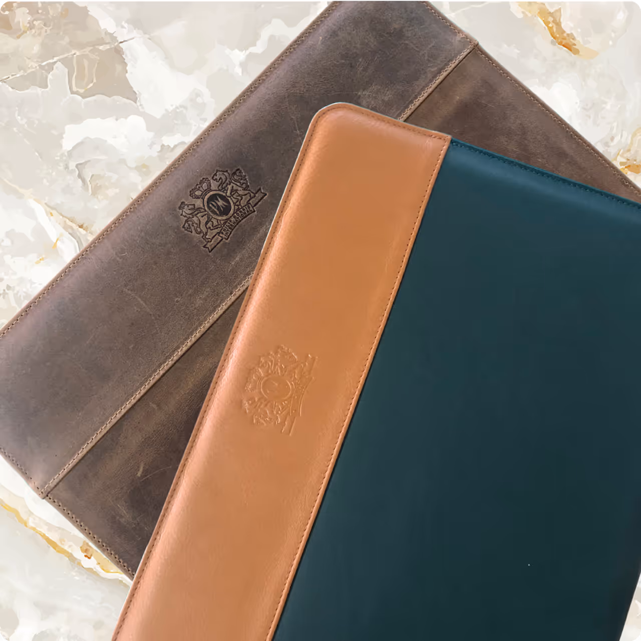 Two luxury leather document or tablet cases with embossed logo on a marble background.