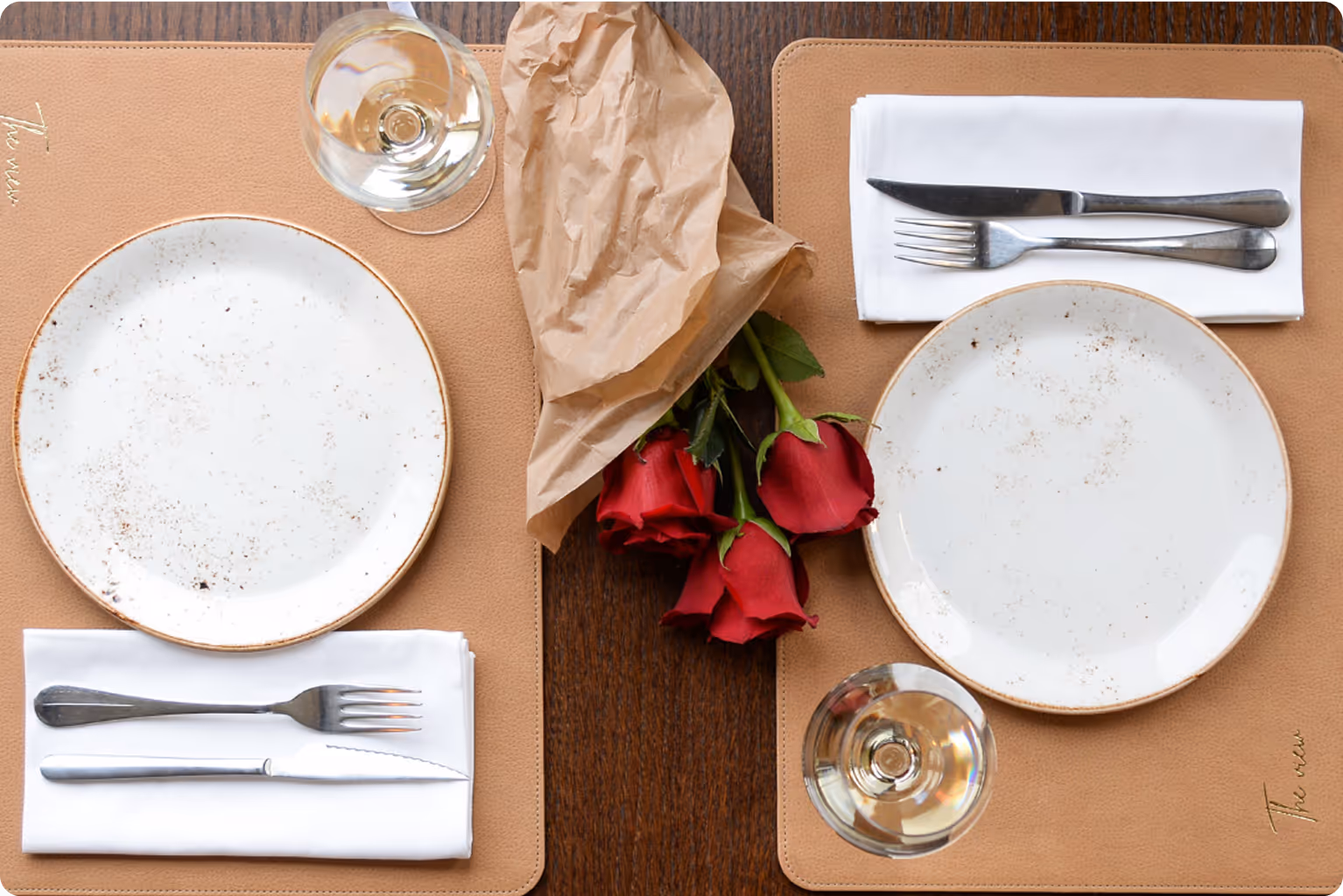 A place setting with a rose and a glass of wine.