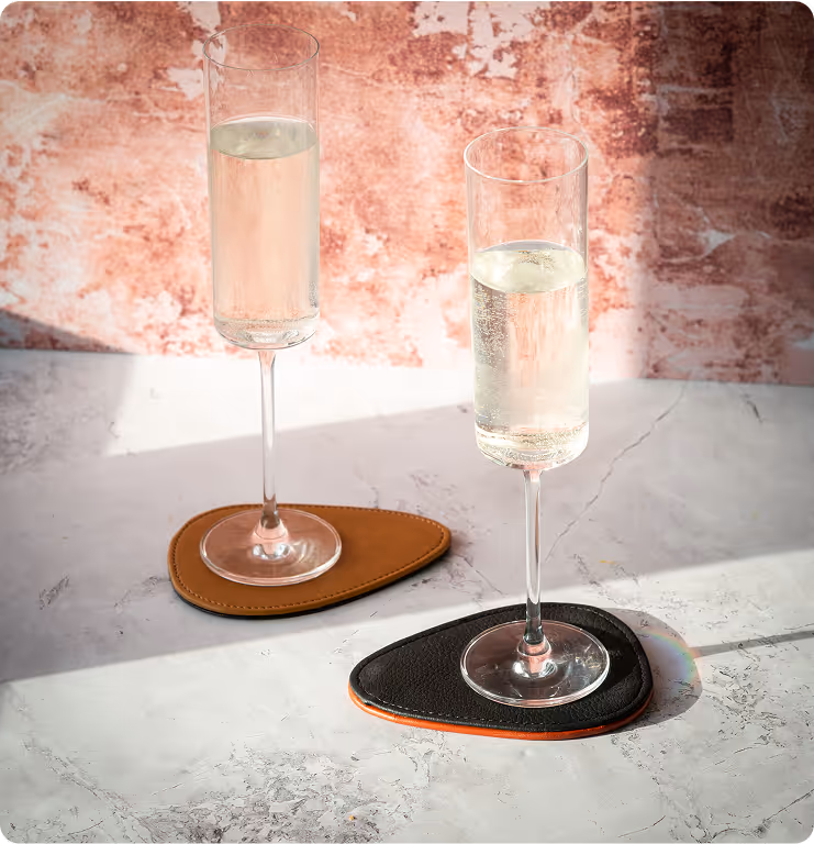 Two glasses of champagne sitting on a coaster.