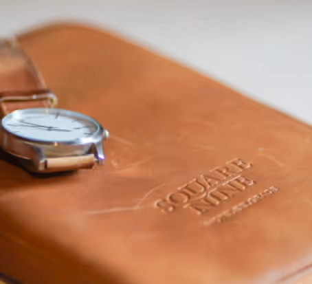 A watch sitting on top of a brown leather case.