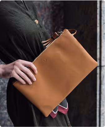 A woman is holding a tan leather purse.