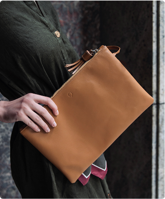A woman is holding a tan leather purse.