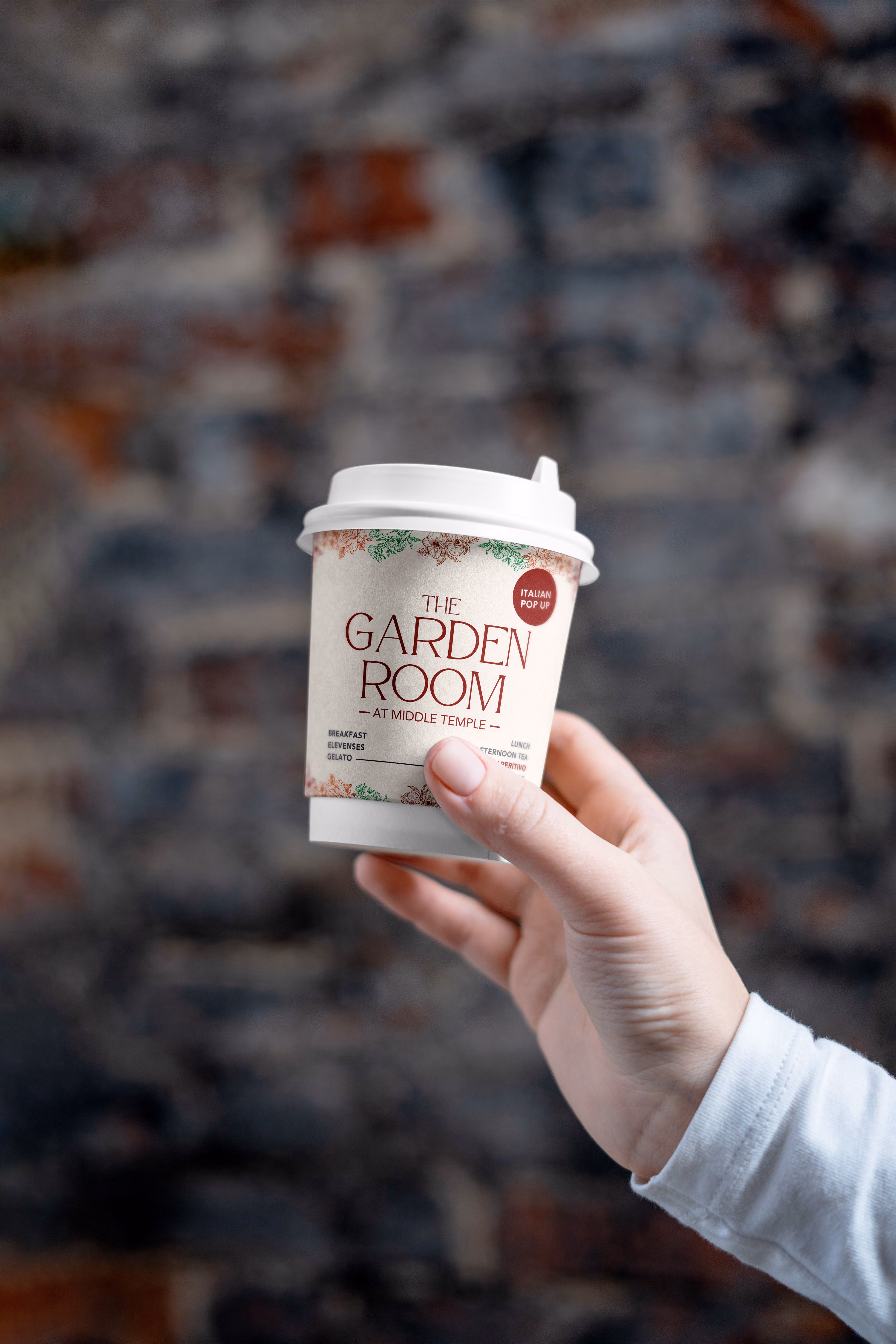 Hand holding a white disposable coffee cup labeled The Garden Room at Middle Temple.