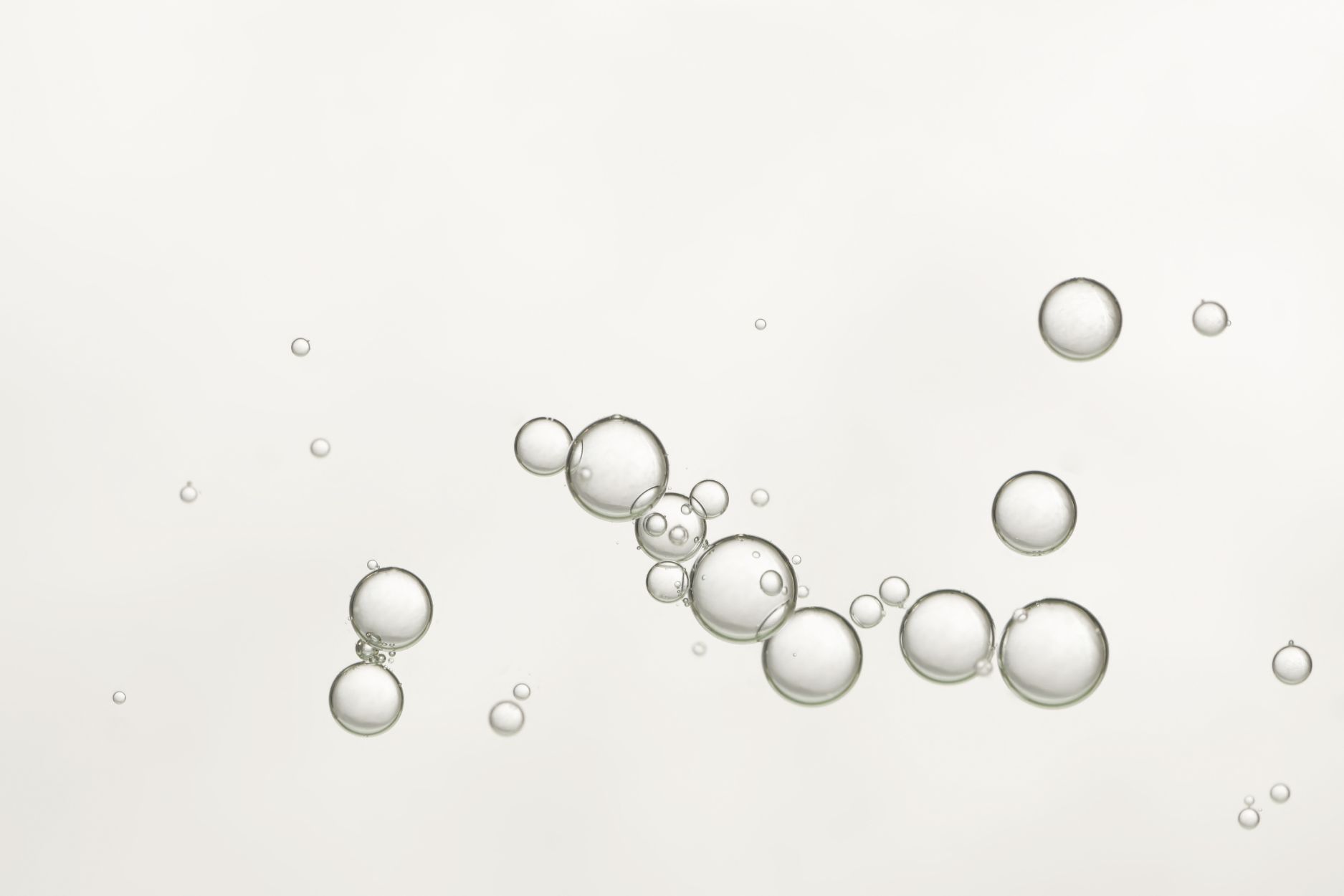 Průhledné bubliny různé velikosti na světlém pozadí.
