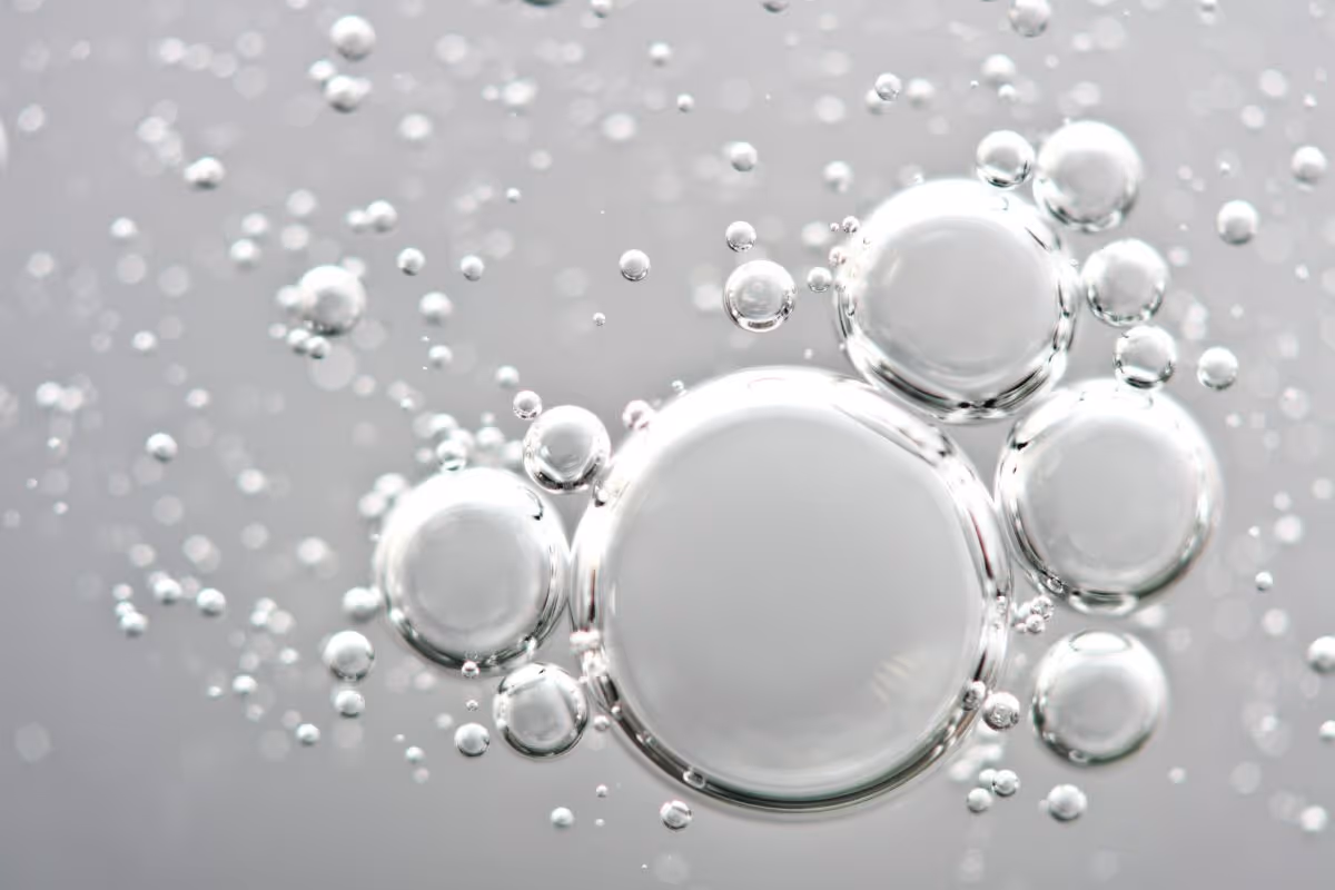 Skupina stříbrných bublin různých velikostí na šedém pozadí.