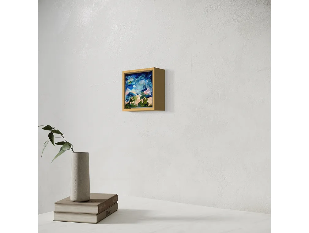 Small framed painting titled "Remember Alone" hangs on a light wall above a table with books and a vase holding a leafy stem.