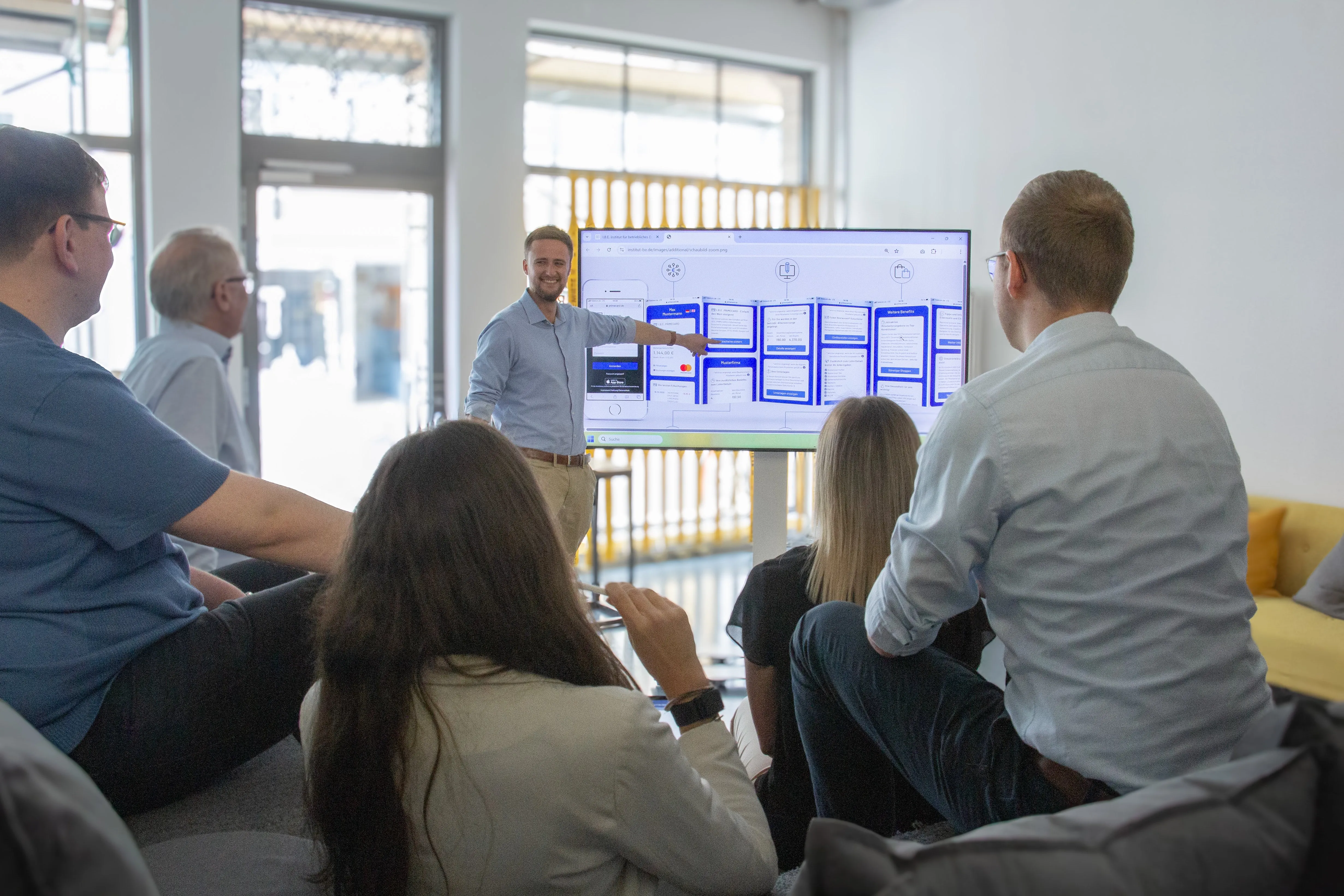 Experte erklärt das Benefit-Tool am TV-Bildschirm – steht für persönliche Einführung und effizienten Support durch LohnVorteil.