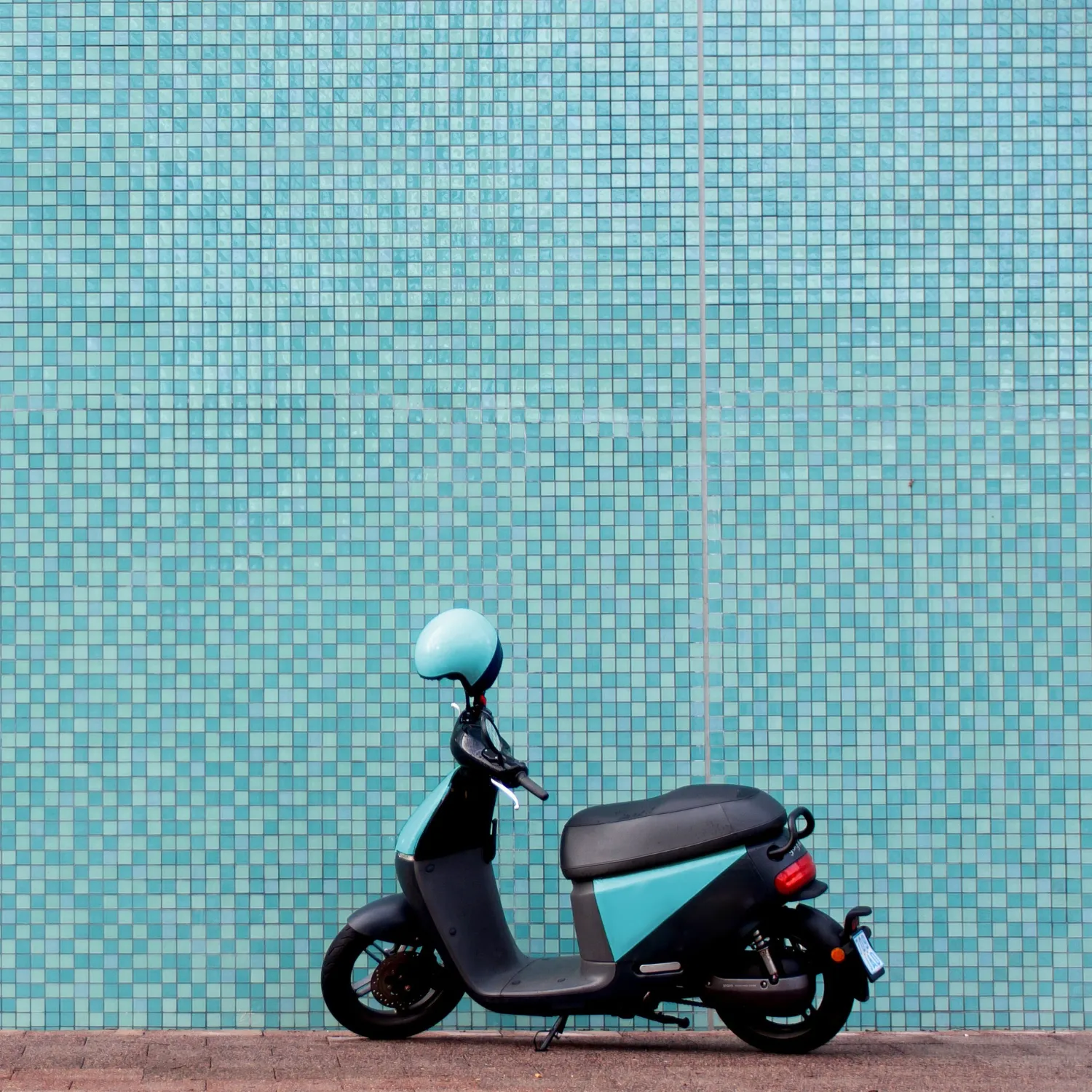 Elektroroller mit blauem Helm vor strukturierter Wand – steht für den steuerfreien Firmen-E-Roller als flexibles Mobilitäts-Benefit für Mitarbeitende.