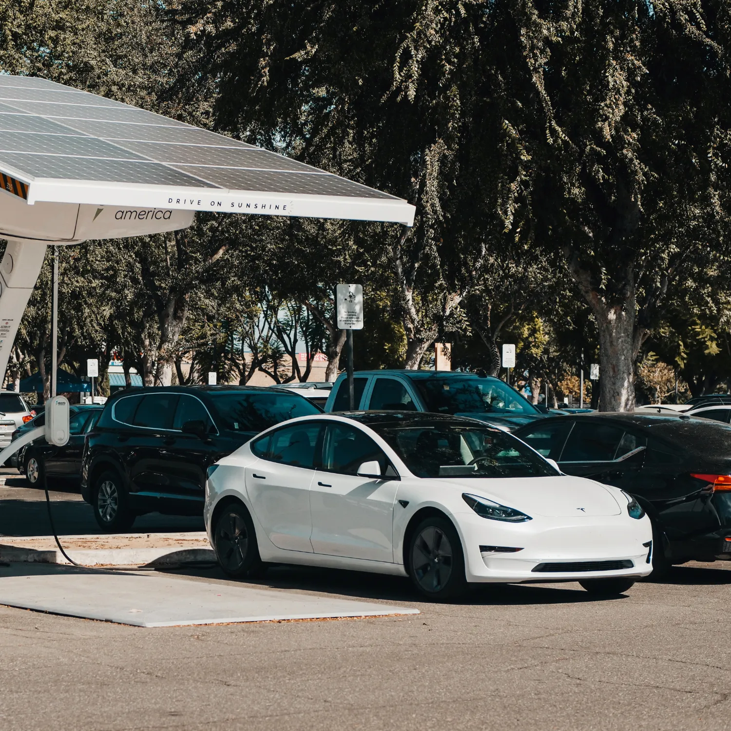 Weiße Elektrofahrzeuge unter Solardach – visualisiert das E-Auto als nachhaltige, steuerlich geförderte Alternative zum klassischen Dienstwagen.