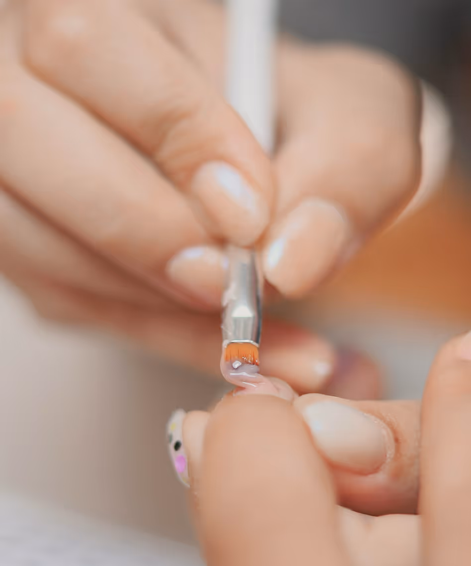 Hand die een nagelverzorger gebruikt om nagellak of gel op een vingernagel aan te brengen met een penseel.