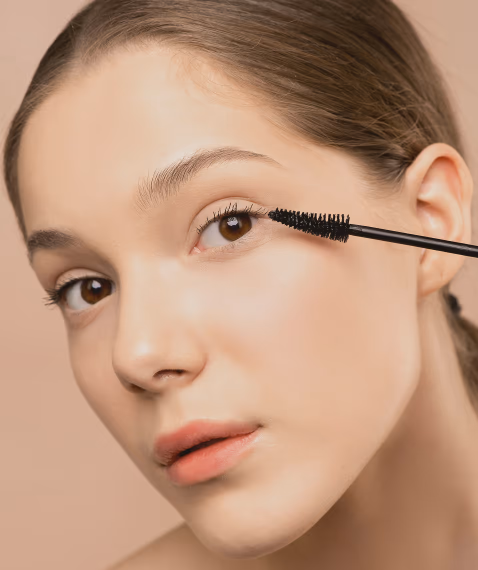 Vrouw die mascara aanbrengt op de wimpers van haar rechteroog.