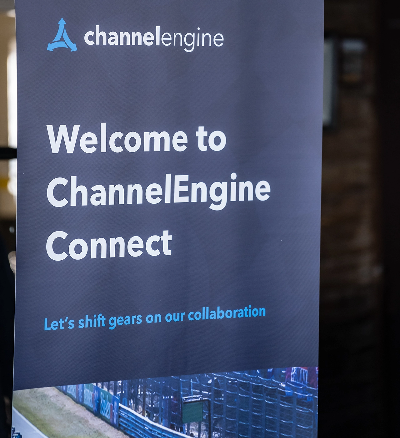 A behind-the-scenes photo captures a woman laughing while sitting behind a table illuminated by spotlights