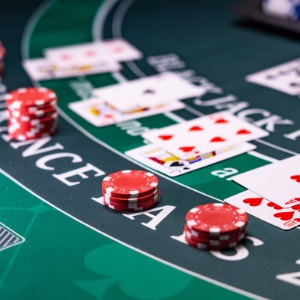 The background is a blackjack table with playing cards and poker chips laid out on it