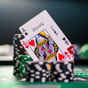 A close up of an ace of spades and queen of hearts playing cards on a stack of poker chips on a blackjack table