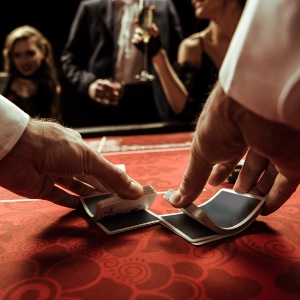 Set in a casino, the croupier shuffling a deck of playing cards onto the table