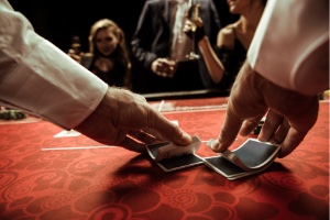 Set in a casino, the croupier shuffling a deck of playing cards onto the table