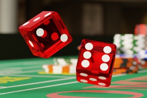 The background is a craps table with poker chips stacked and two red dynamic dice rolling in the centre of the image