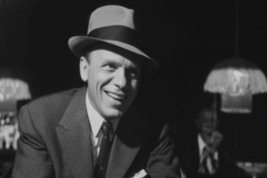 A man similar to Frank Sinatra sitting at a games table in a casino