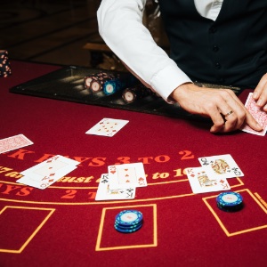 A red felt topped blackjack table with the dealer about to deal another card