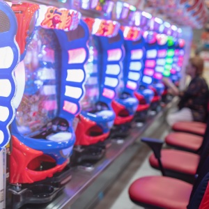 A man sitting infront of a machine playing Pachinko