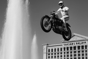 A man dressed in all white riding a motorbike over a fountain outside a hotel in Las Vegas