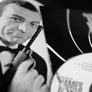 A black and white image of Sean Connery holding in a James Bond movie style image