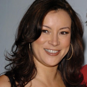 A close up image of Jennifer Tilly with her hair and makeup done and wearing gold hoop earrings