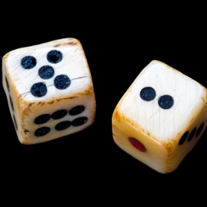 An image with a black background and in the centre are two old dice made of bone