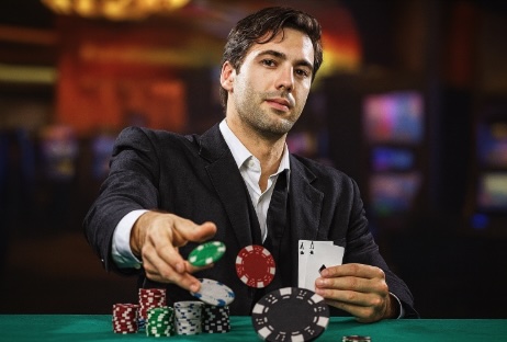 An image of a poker player sitting at a green felt table holding 2 aces tossing poker chips across the table