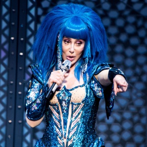 An image of Cher dressed in full performaance costume and wig at an event singing