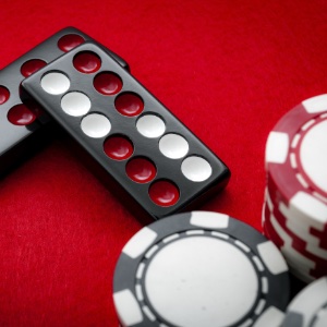 An image of Pai Gow dominoes and poker chips on a red flet table background