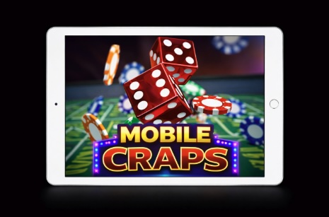 An image of a silver ipad on a black background, on the screen is a MOBILE CRAPS image with red dice and poker chips